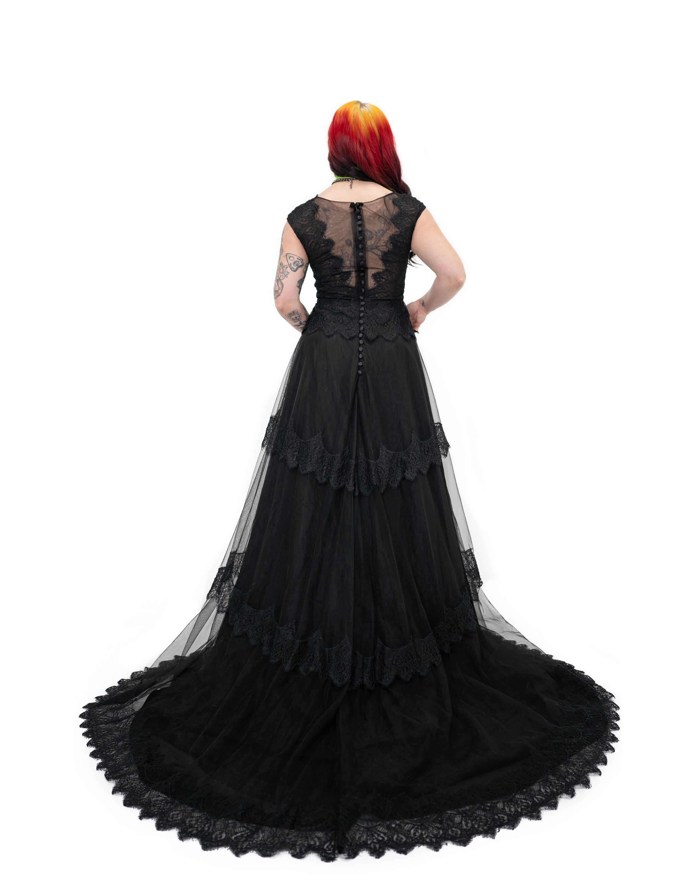 Back view of Bête Noire Devotion gown with zipper closure and decorative buttons, sheer lace bodice and train.