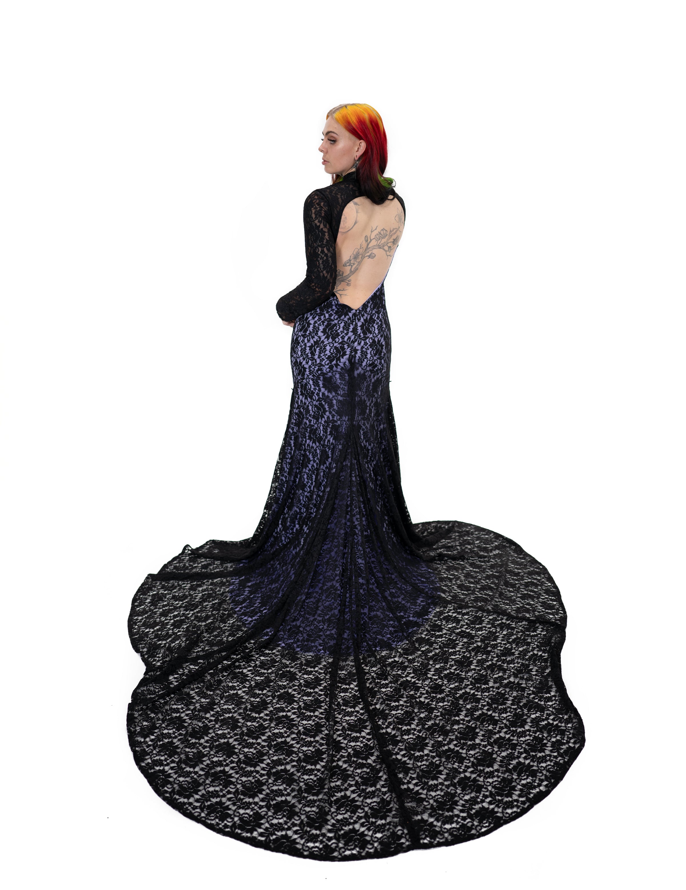 Back view of the Evangeline gown by Bête Noire with an open back and long black lace train over a purple underlay