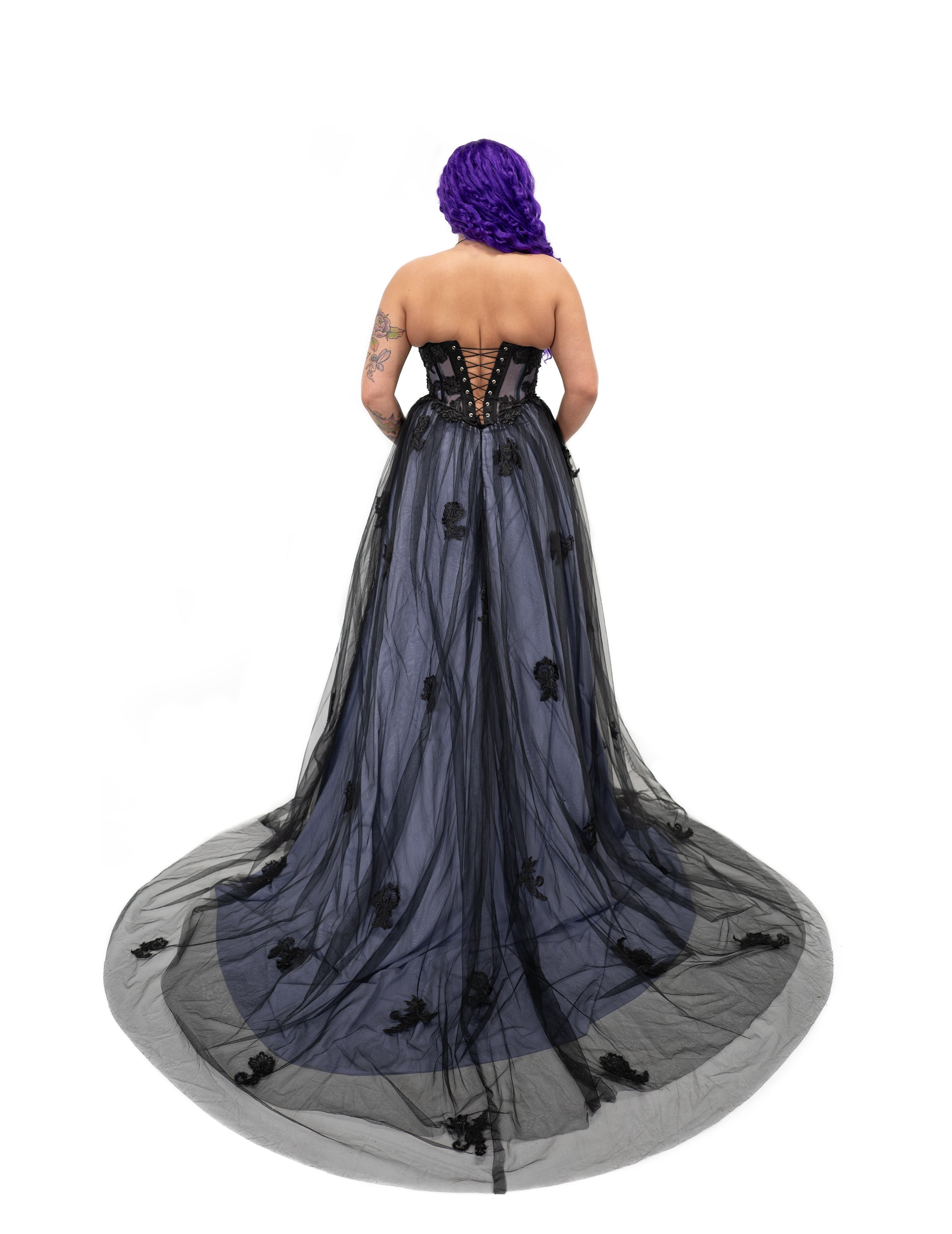 Back view of a black and purple alternative bridal gown with a corset lace-up back and long sheer tulle train.