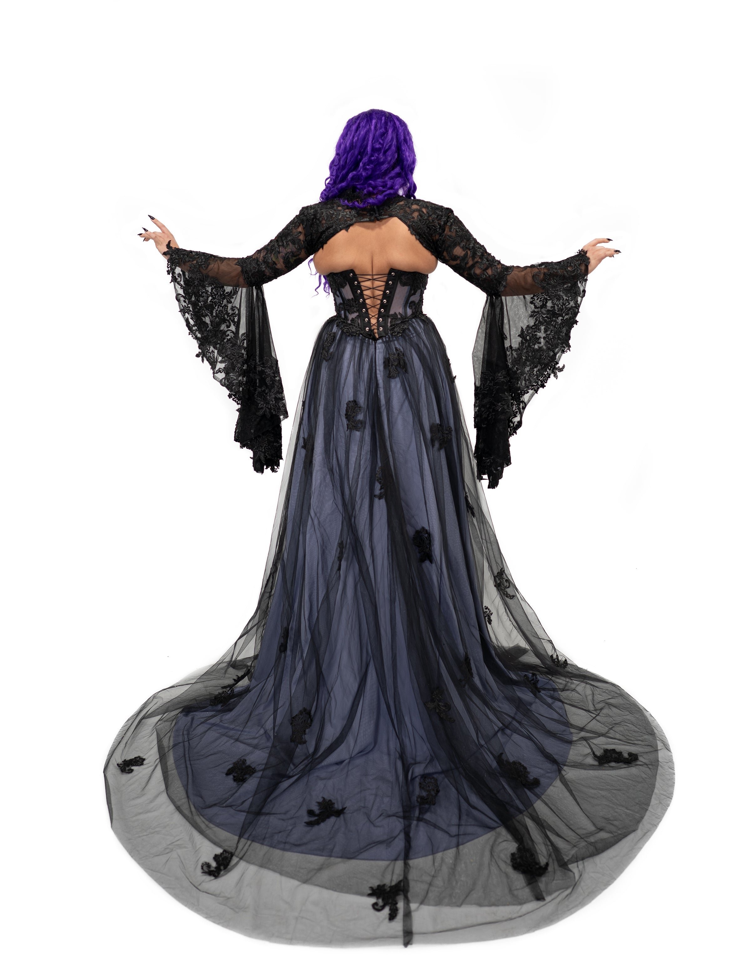 Back view of the violet gothic bridal dress with a black lace bolero featuring dramatic bell sleeves over a corset back.