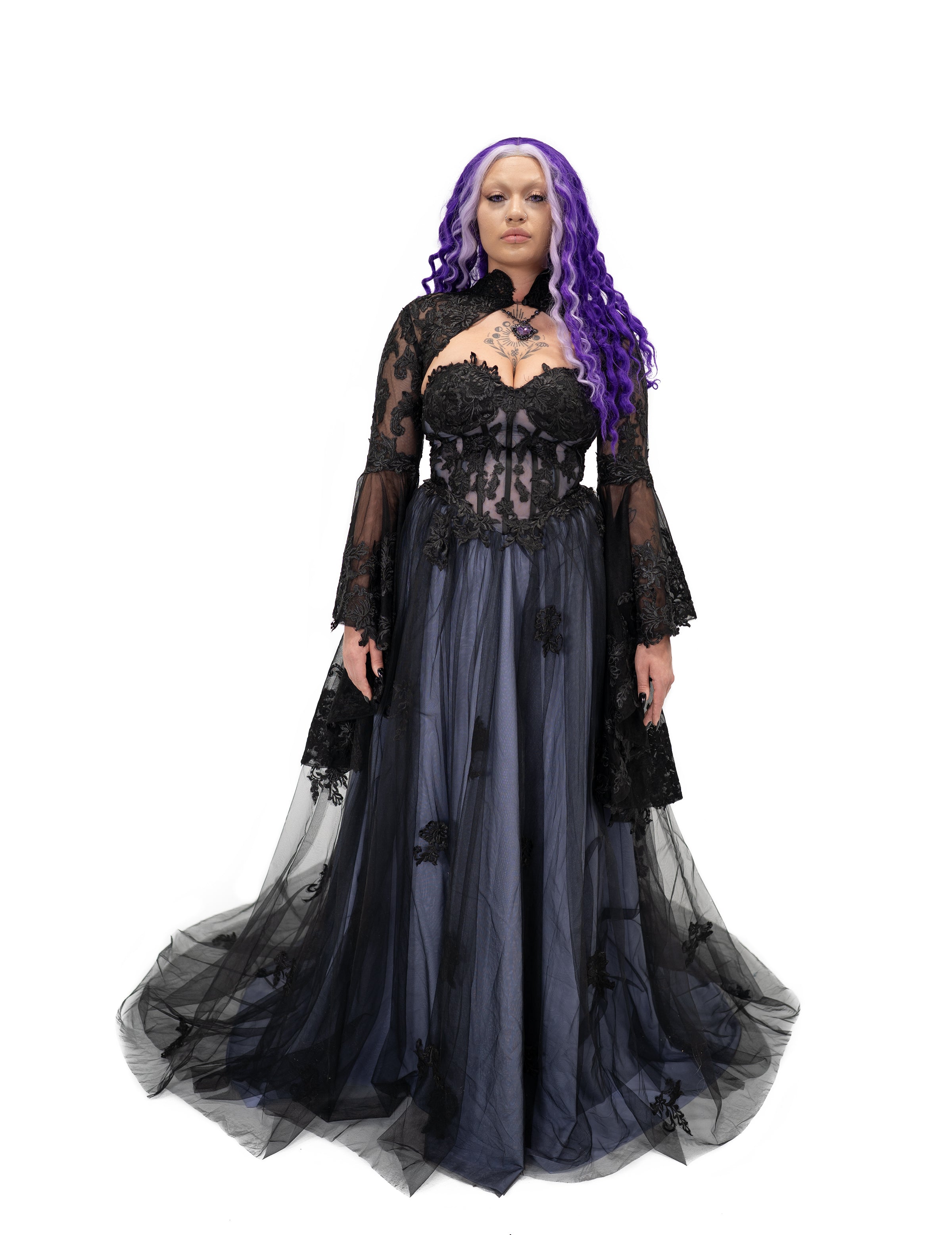 Front view of the violet alternative bridal gown styled with a sheer black lace bolero and bell sleeves over a corset bodice.